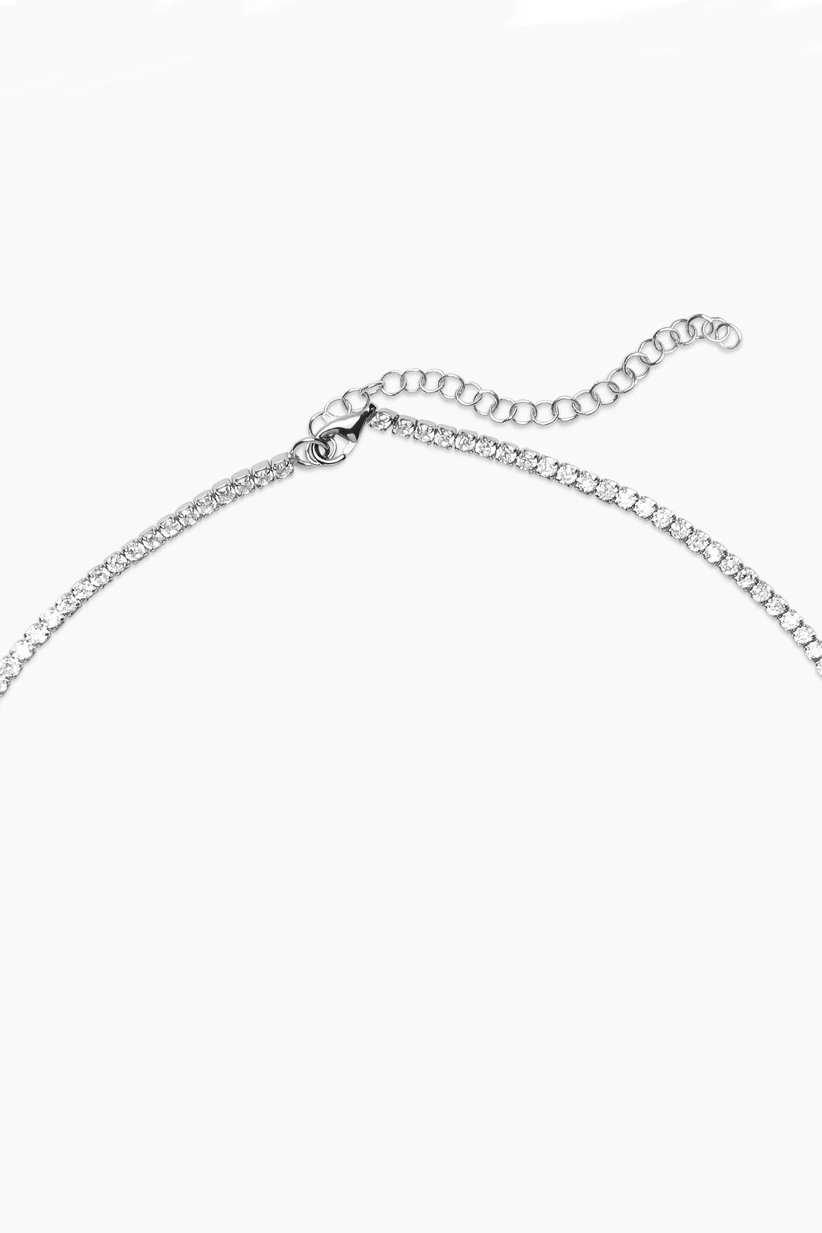   The GLIMMER NECKLACE BY PHYLLIS AND ROSIE features a silver chain adorned with small, evenly spaced round stones and an adjustable clasp, drawing inspiration from Phyllis+Rosie's interpretation of New York City jewelry and vintage street culture. 