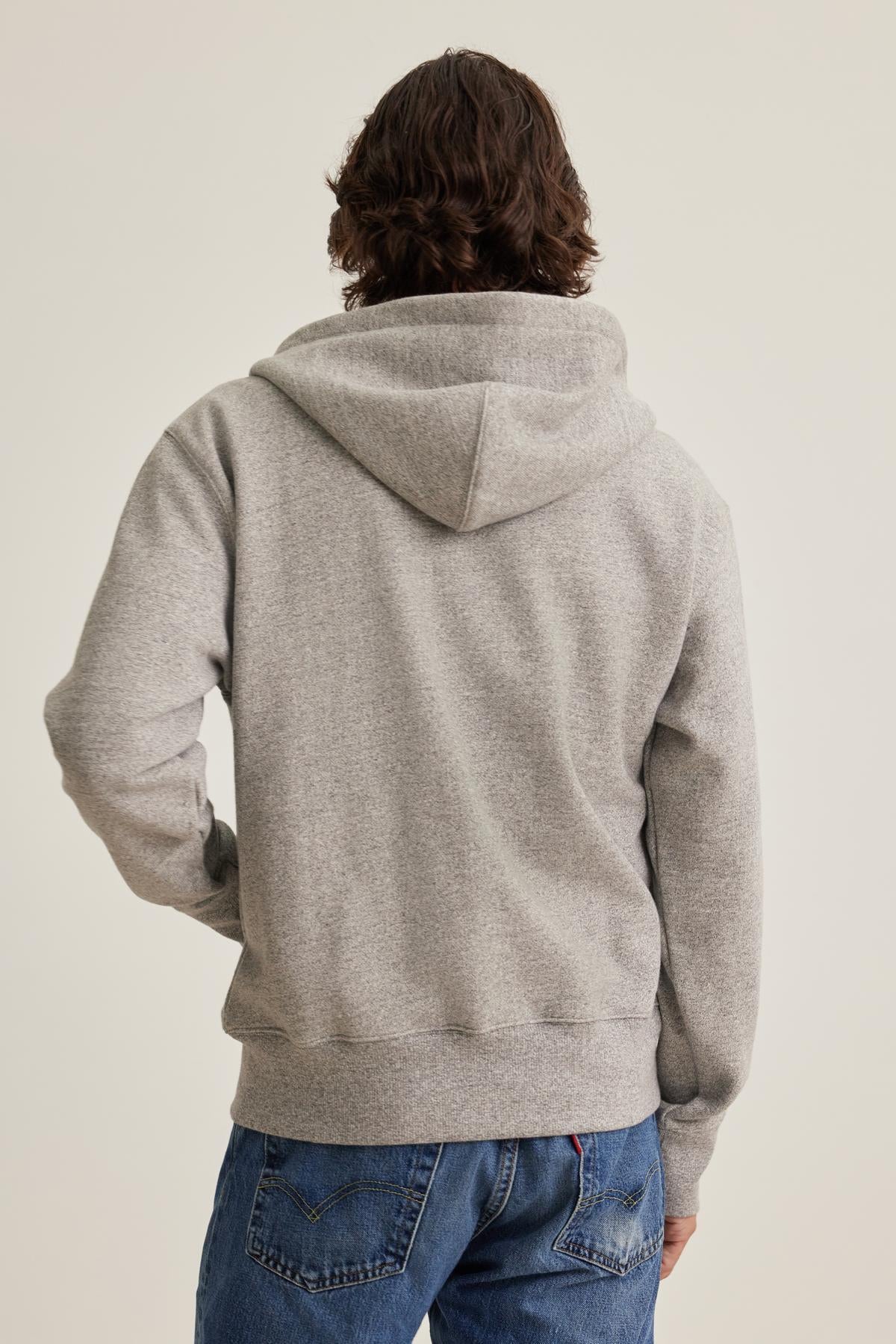   Individual with long hair in a DRACO HOODIE by Velvet by Graham & Spencer, paired with blue jeans, facing away. 