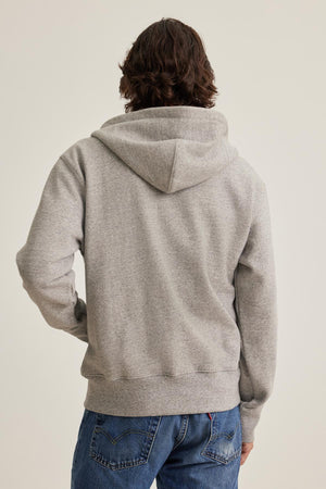 Individual with long hair in a DRACO HOODIE by Velvet by Graham & Spencer, paired with blue jeans, facing away.