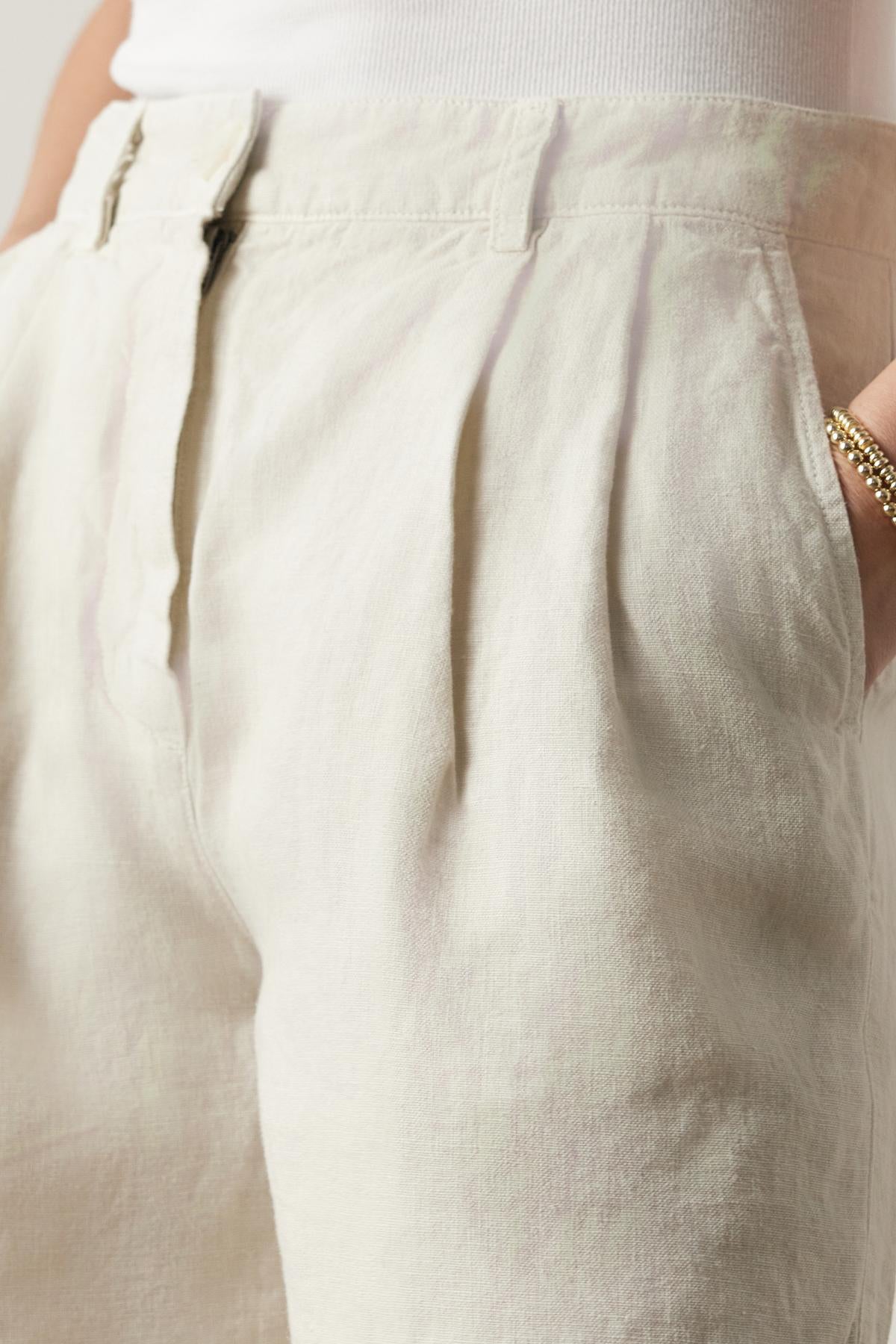   Close-up of a person wearing Velvet by Jenny Graham's LARCHMONT HEAVY LINEN SHORTS and a white top, focusing on the fabric texture and pocket detail. 