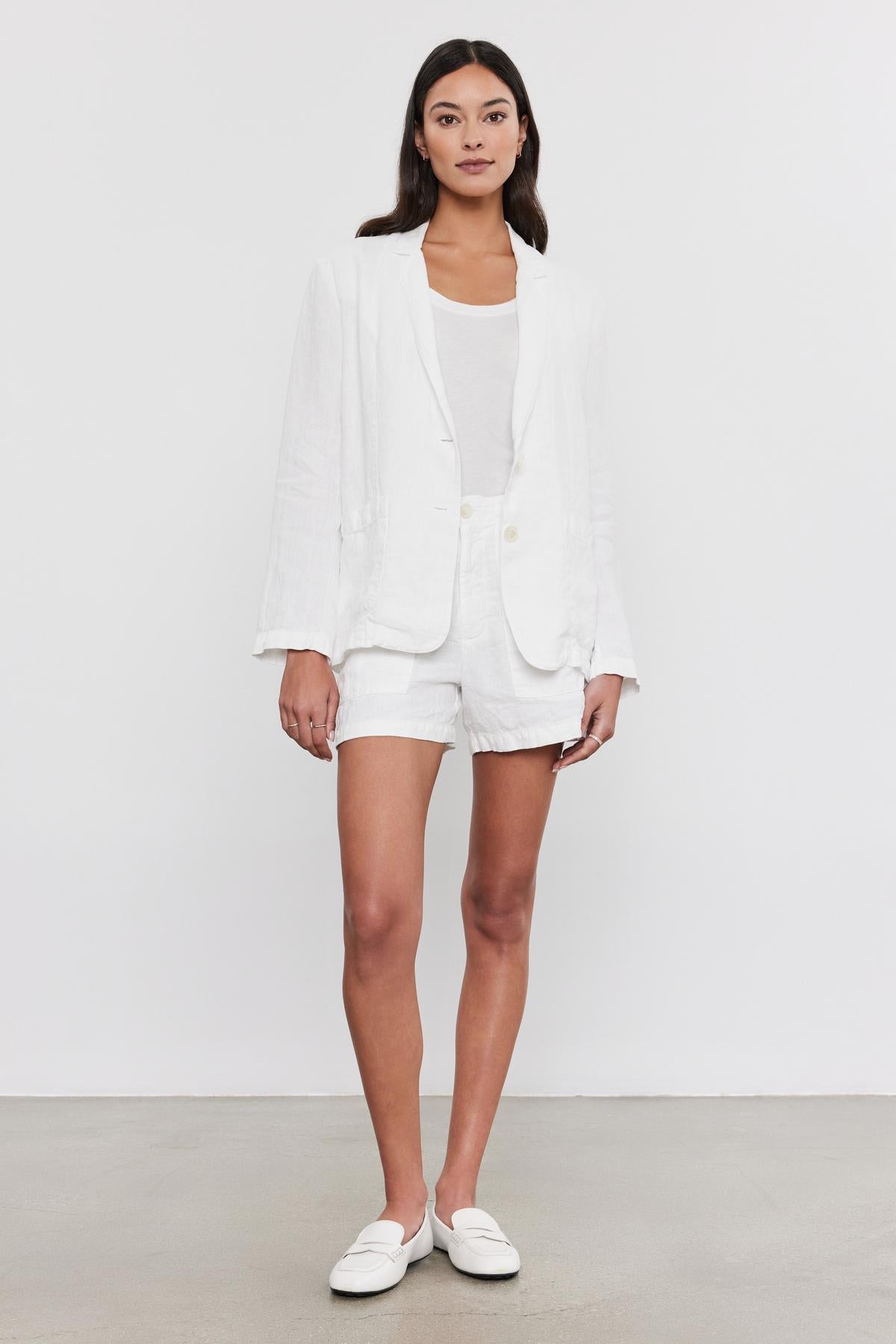 Woman in a Velvet by Graham & Spencer LENNY HEAVY LINEN BLAZER and shorts set with a white top, standing against a plain background, wearing white loafers.-36910096285889