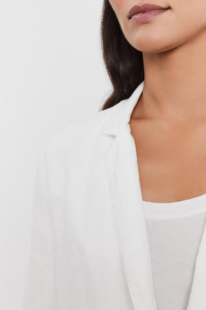 Close-up of a woman wearing a Velvet by Graham & Spencer LENNY HEAVY LINEN BLAZER over a white t-shirt, focusing on her lower face and neckline.