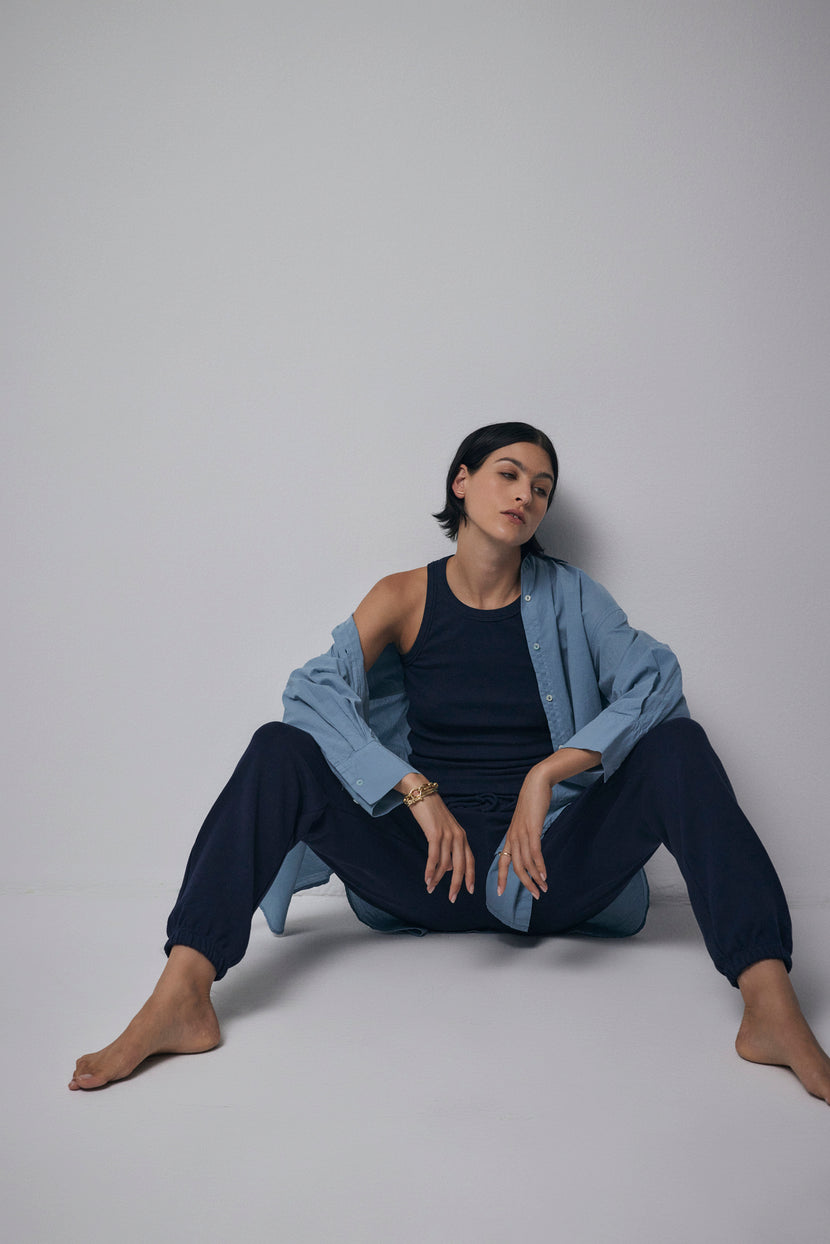 A woman sitting on the floor in a Velvet by Jenny Graham WESTLAKE SWEATPANT and blue shirt.