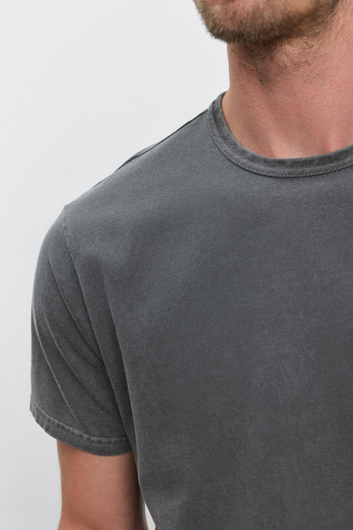   A person wearing Velvet by Graham & Spencer's STITCH TEE, a plain, gray, short-sleeve T-shirt. The image is cropped to show only the neck, shoulders, and upper chest area. 