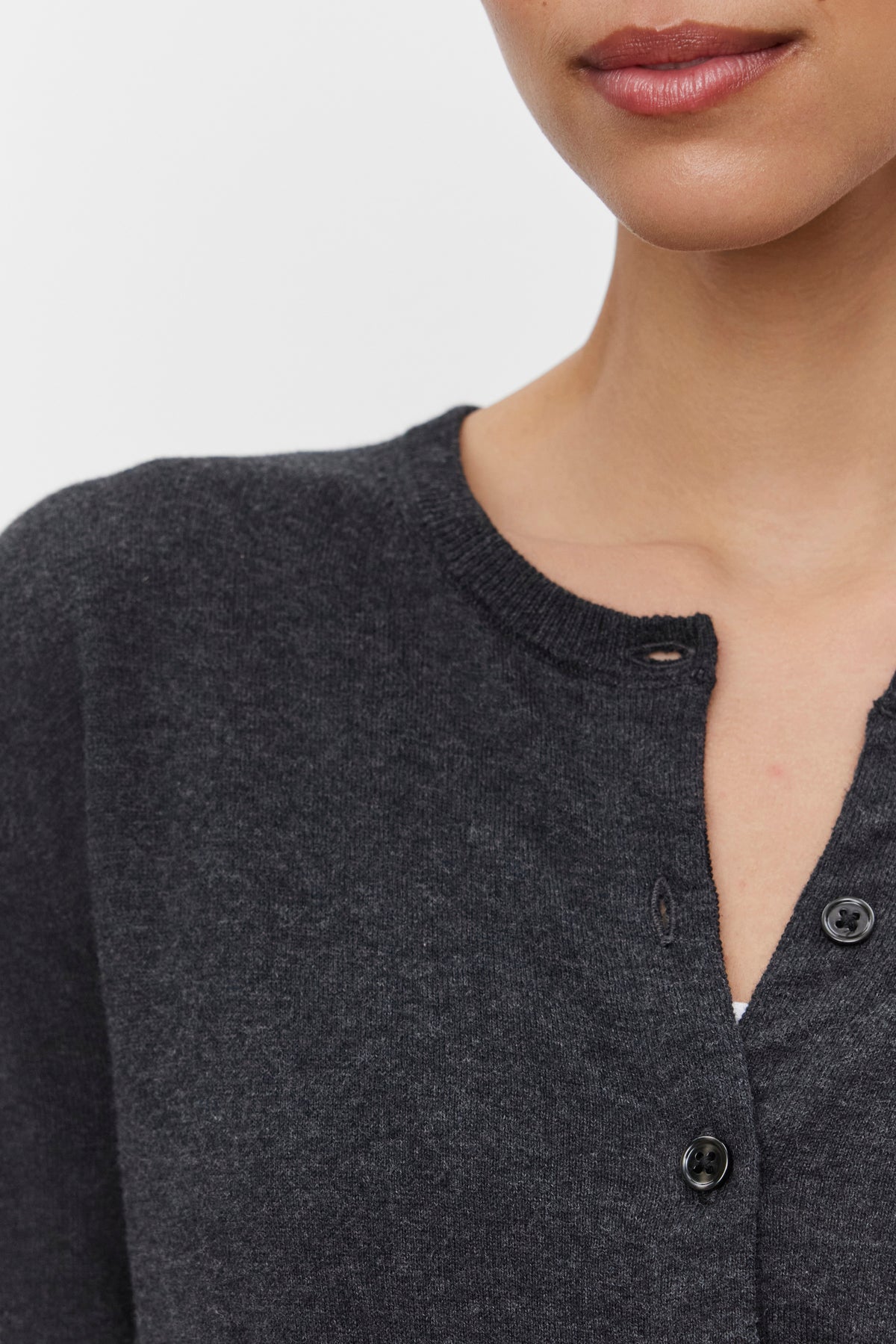   Close-up of a person wearing the VIOLETTE CARDIGAN by Velvet by Graham & Spencer, with two buttons fastened and one unbuttoned. Only the lower half of their face and part of their torso are visible. 