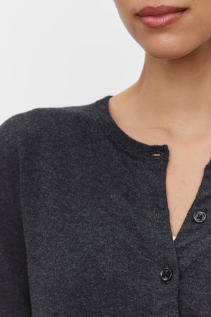 Close-up of a person wearing the VIOLETTE CARDIGAN by Velvet by Graham & Spencer, with two buttons fastened and one unbuttoned. Only the lower half of their face and part of their torso are visible.