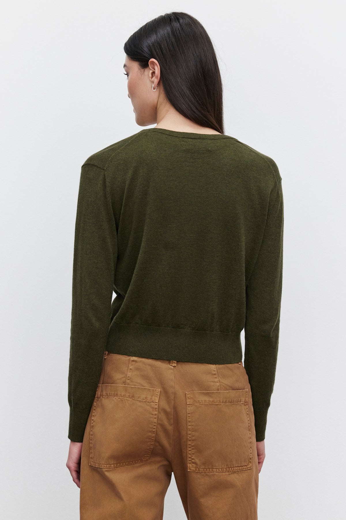   A woman with long dark hair is shown from the back wearing an olive green VIOLETTE CARDIGAN by Velvet by Graham & Spencer and brown pants. 