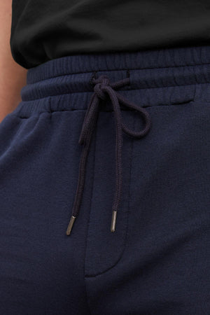 Close-up of ATLAS SHORT in navy blue, offering a tailored design with an adjustable drawstring, effortlessly paired with a black top from Velvet by Graham & Spencer.