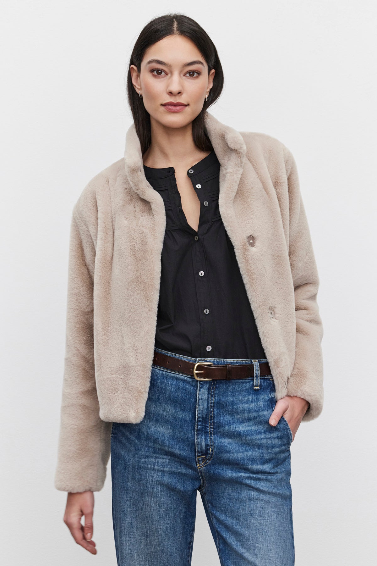   A person wearing the SHEENA LUXE FAUX FUR JACKET by Velvet by Graham & Spencer over a black shirt and blue jeans, standing against a plain white background. 