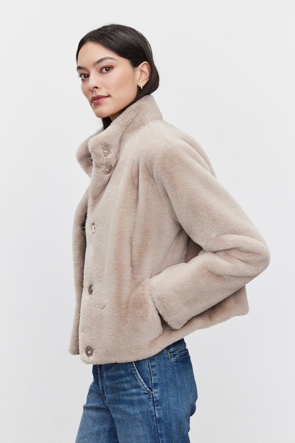   A woman wearing the SHEENA LUXE FAUX FUR JACKET by Velvet by Graham & Spencer, paired with blue jeans, stands against a plain background. 