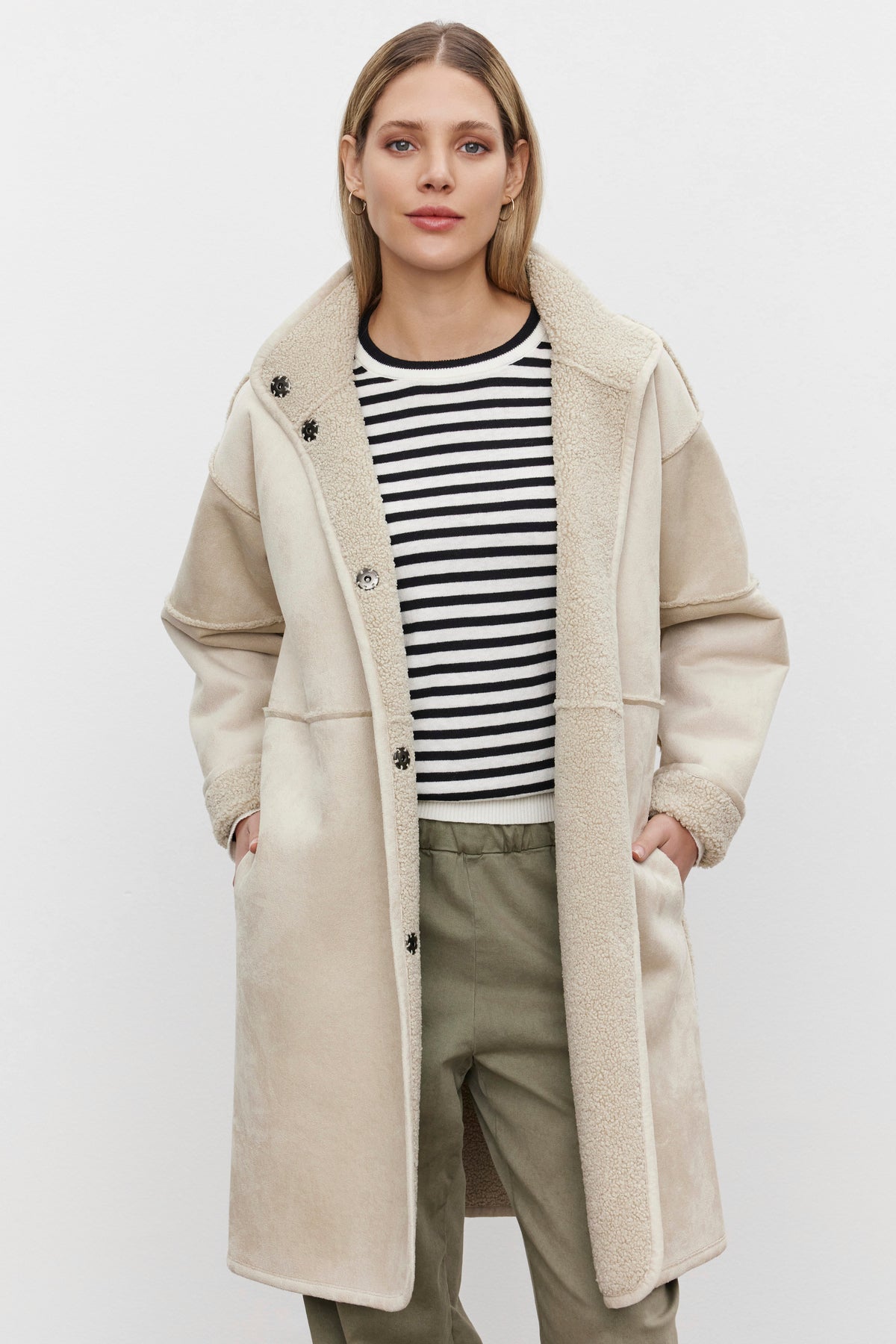 A person wearing a Velvet by Graham & Spencer's CARA LUXE SHERPA REVERSIBLE JACKET over a black and white striped shirt and olive pants, standing against a plain background.-37893996675265