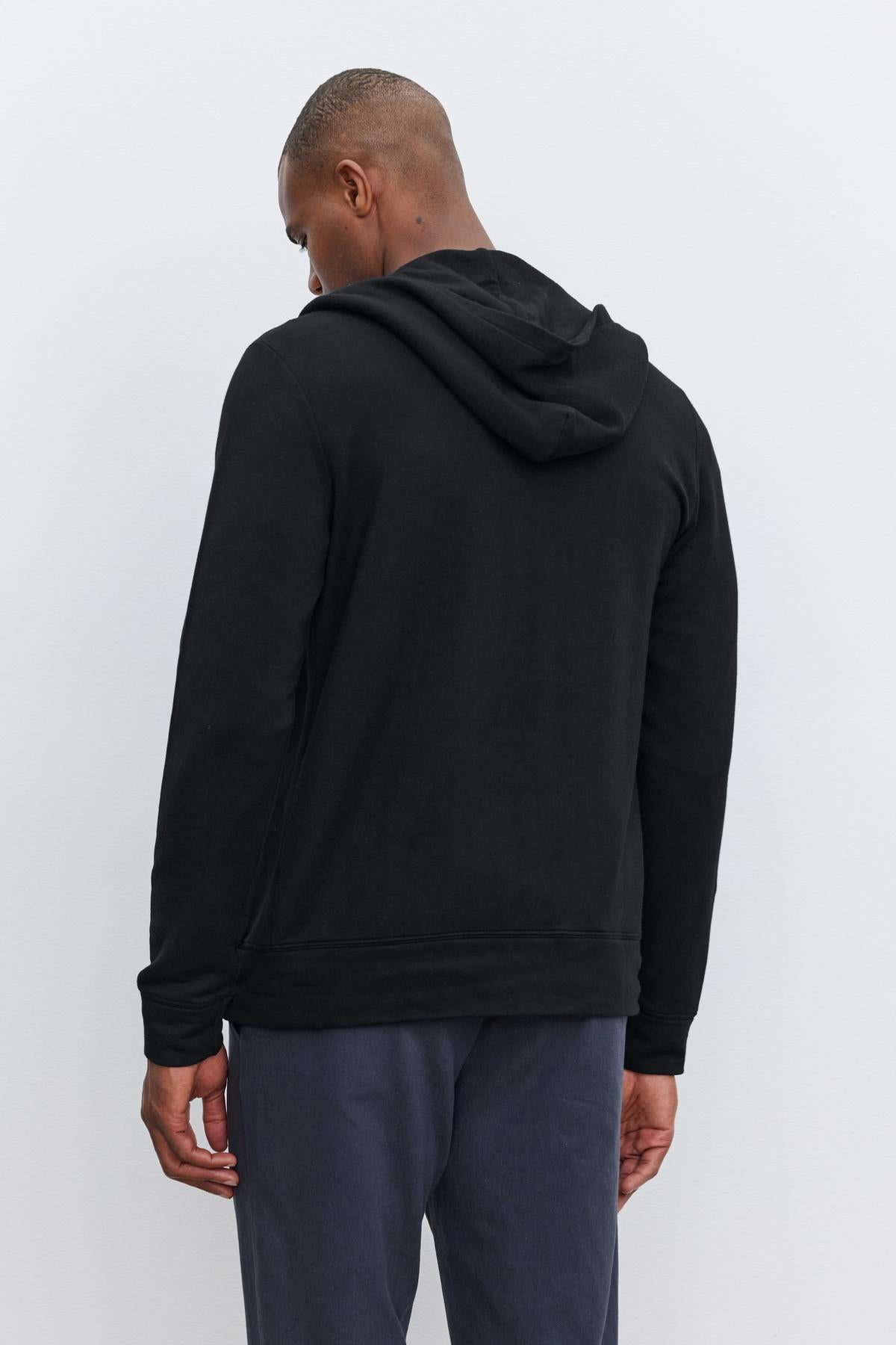   A person wearing a Velvet by Graham & Spencer RODAN HOODIE and dark pants is facing away from the camera against a plain white background. 