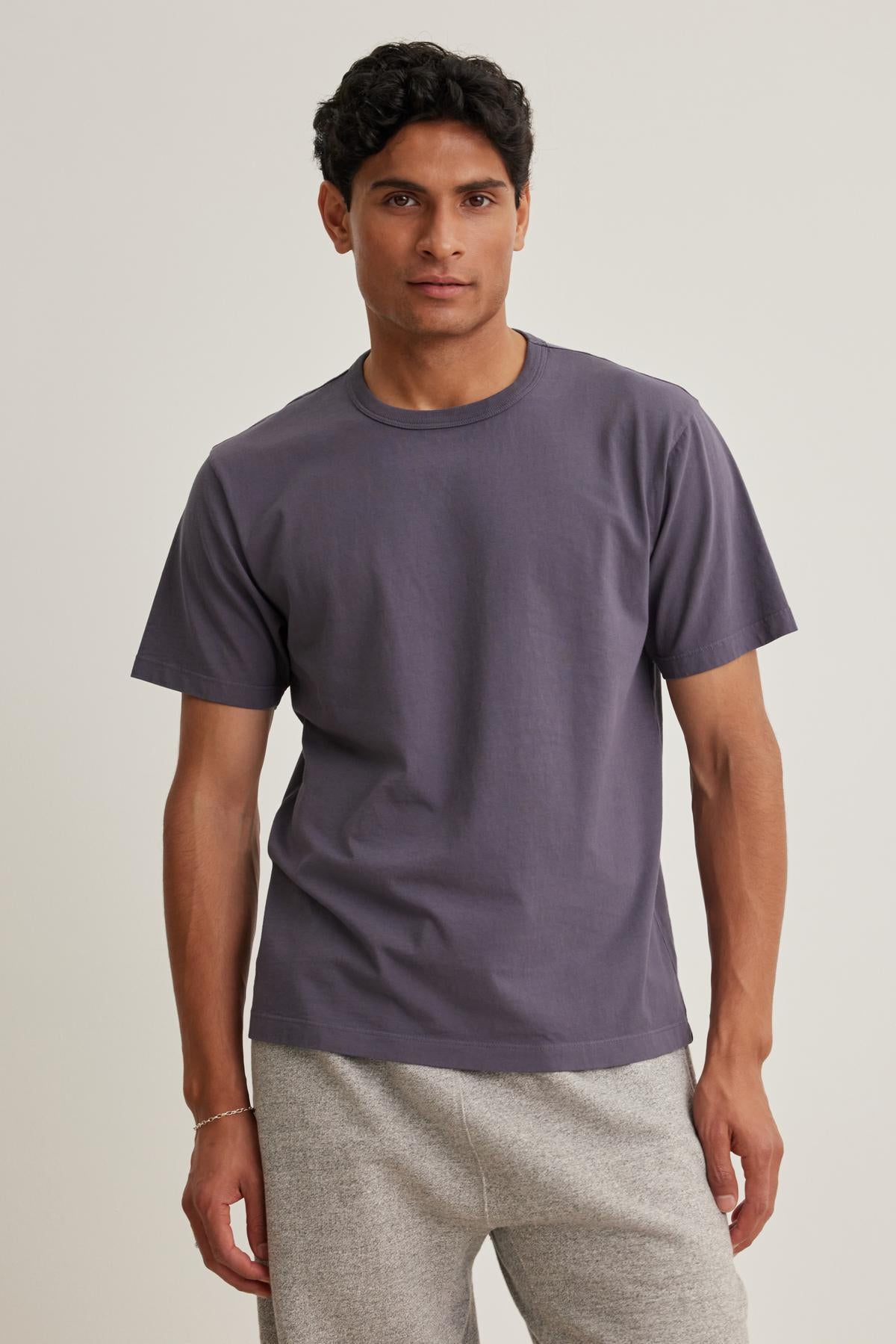 A man wearing the WELLS TEE by Velvet by Graham & Spencer and light gray pants stands against a neutral background.-38643375898817