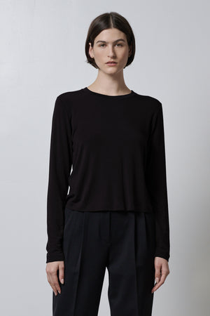 The model is wearing a black Velvet by Jenny Graham rib knit long sleeved top and stretch trousers.