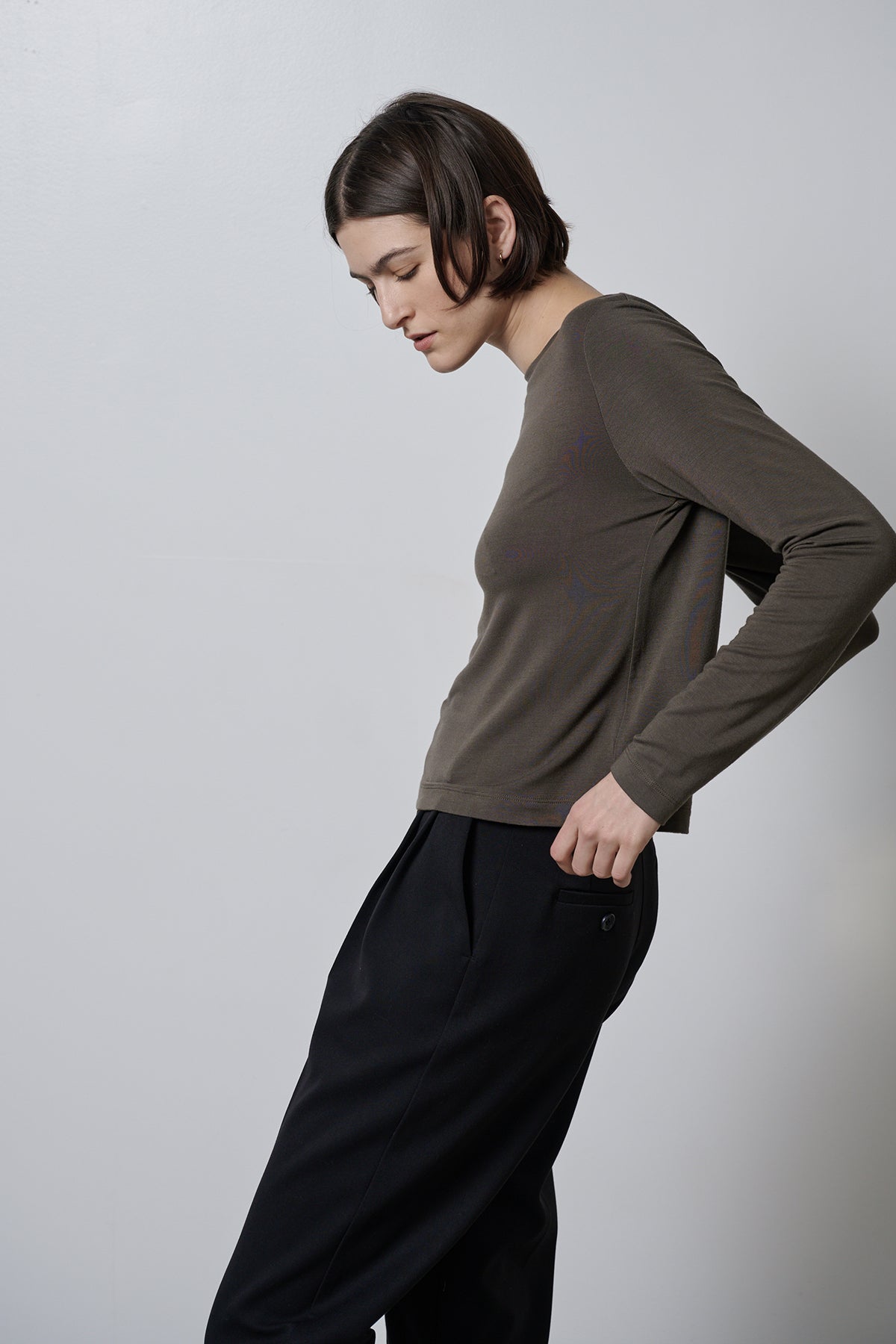   A woman wearing black trousers made of rib knit fabric and a Velvet by Jenny Graham long-sleeved Pacifica Tee with a soft hand feel. 