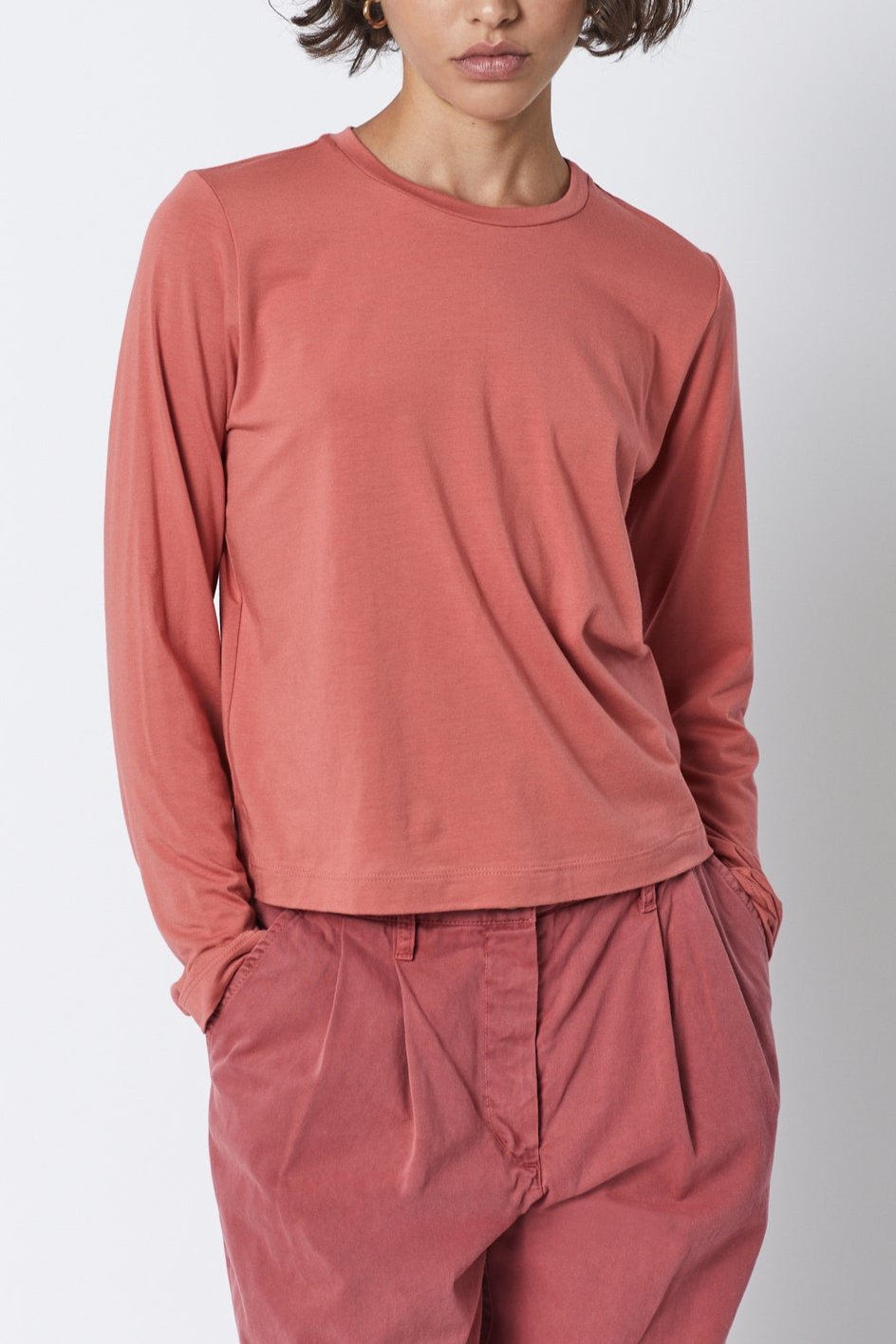   The model is wearing a Velvet by Jenny Graham pink long-sleeved PACIFICA TEE with a soft hand and pleated pants. 