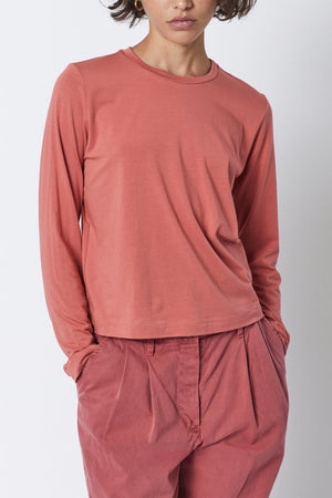 The model is wearing a Velvet by Jenny Graham pink long-sleeved PACIFICA TEE with a soft hand and pleated pants.