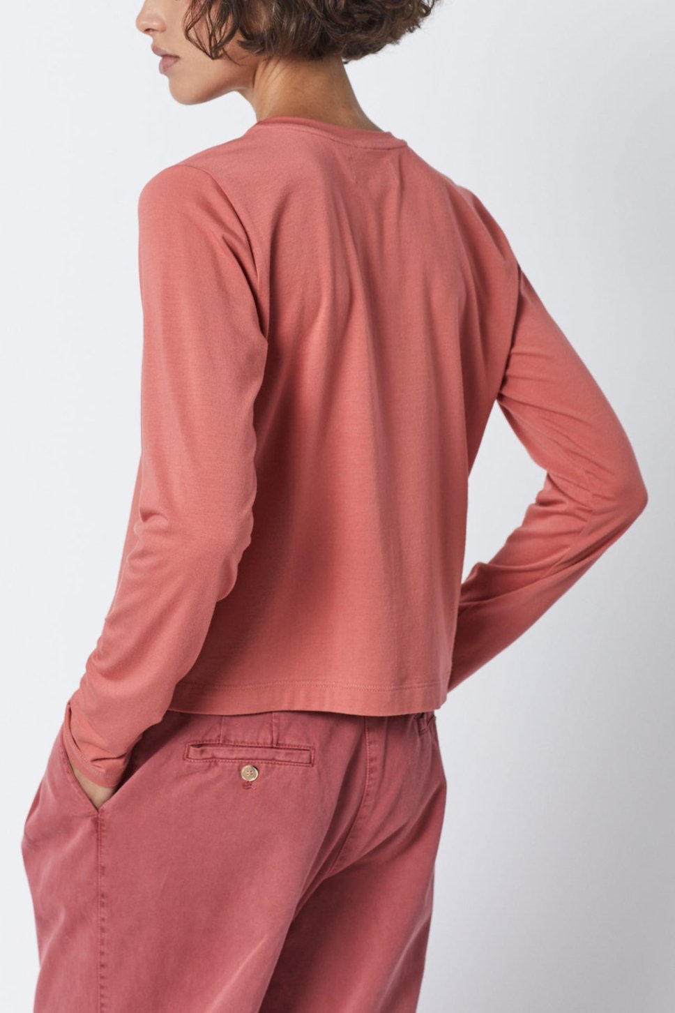 The back view of a woman wearing pink pants and a long-sleeved Velvet by Jenny Graham PACIFICA TEE made from rib knit fabric.-35495909621953