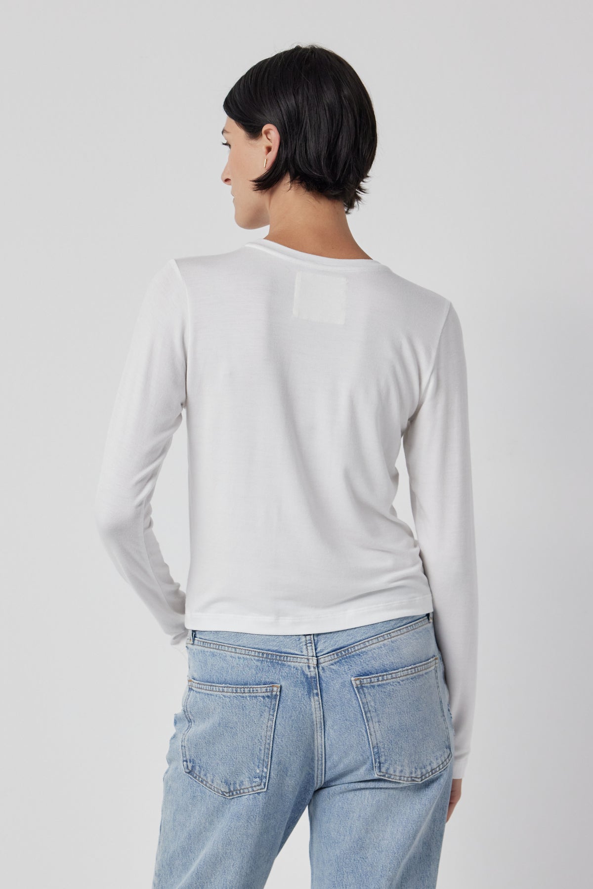   The back view of a woman wearing Velvet by Jenny Graham stretch jeans and a white long-sleeved Pacifica Tee. 