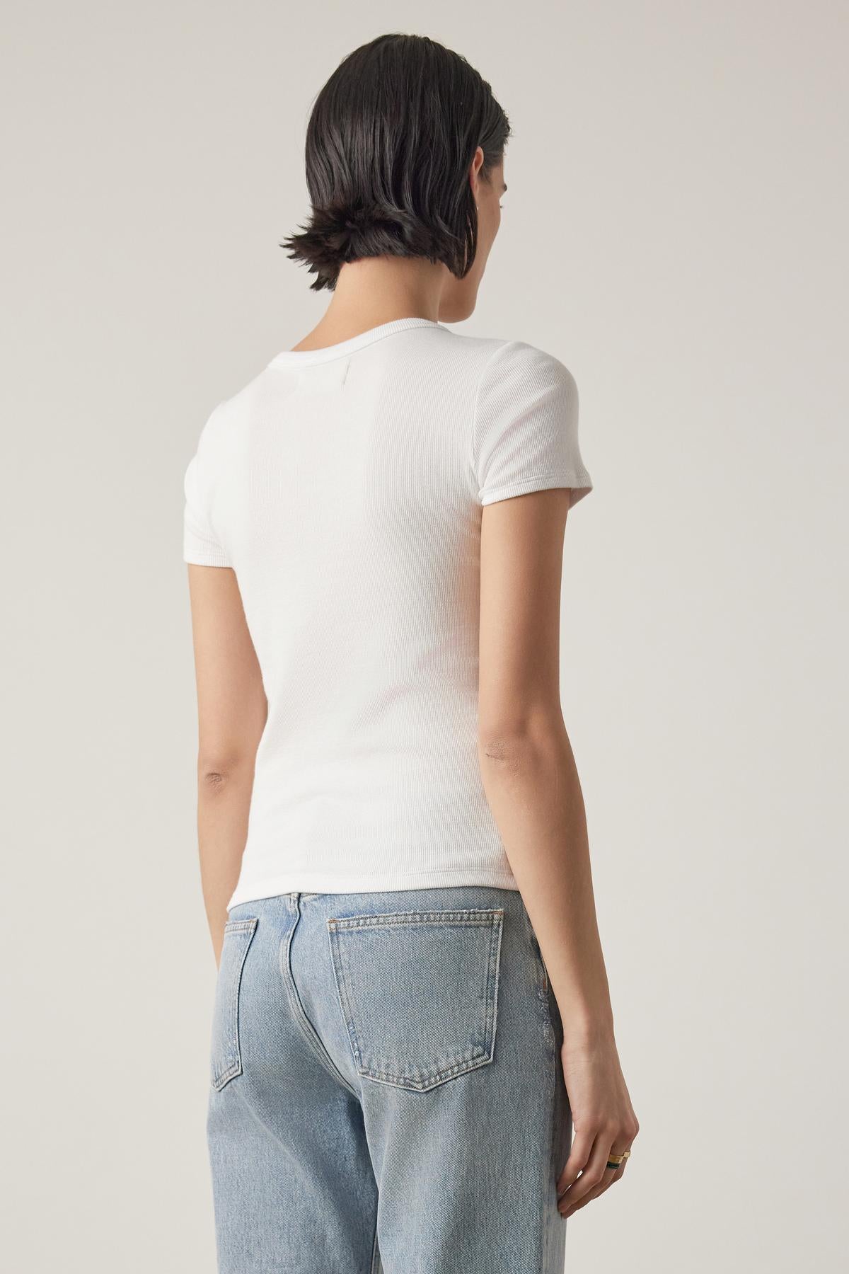   Rear view of a woman in a white BEDFORD TEE from Velvet by Jenny Graham with a crew neckline and blue jeans, focusing on the fit of the clothes. 