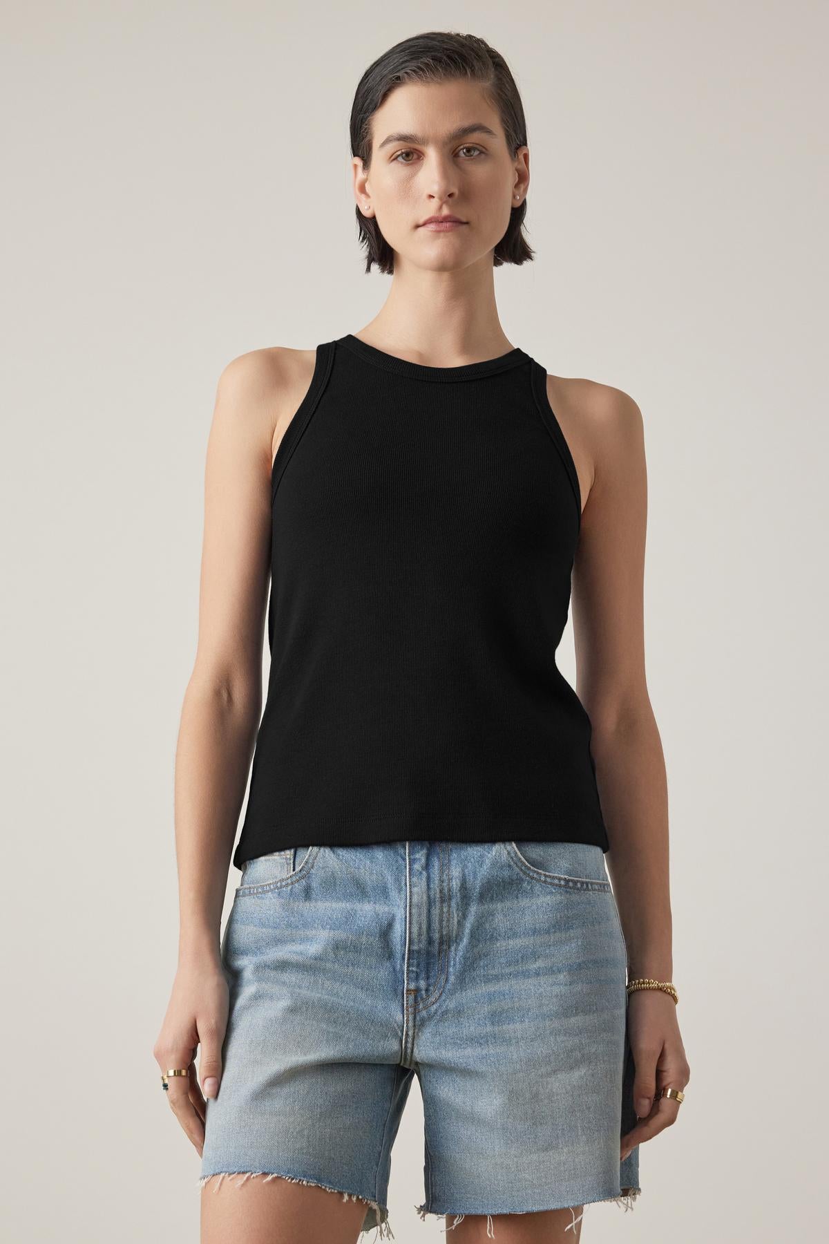   Person wearing the CRUZ TANK TOP by Velvet by Jenny Graham in a ribbed cotton-modal blend and denim shorts, standing against a plain background. 