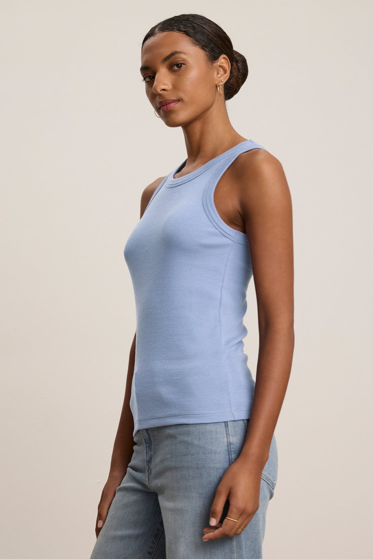 A person wearing the CRUZ TANK TOP by Velvet by Jenny Graham, a versatile light blue ribbed cotton-modal blend piece, pairs it with blue jeans against a plain background.-38662658425025