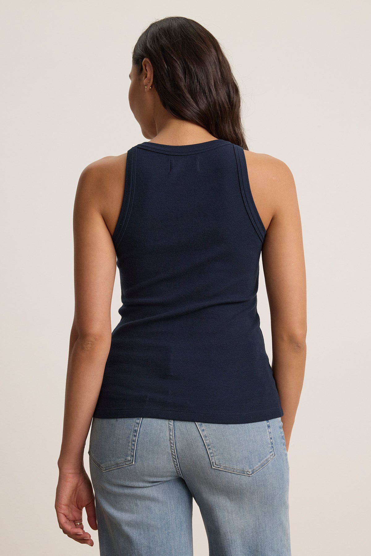   A person with long hair is facing away, wearing a Velvet by Jenny Graham CRUZ TANK TOP in navy blue and light blue jeans. The top is sleeveless and made from ribbed cotton-modal. 