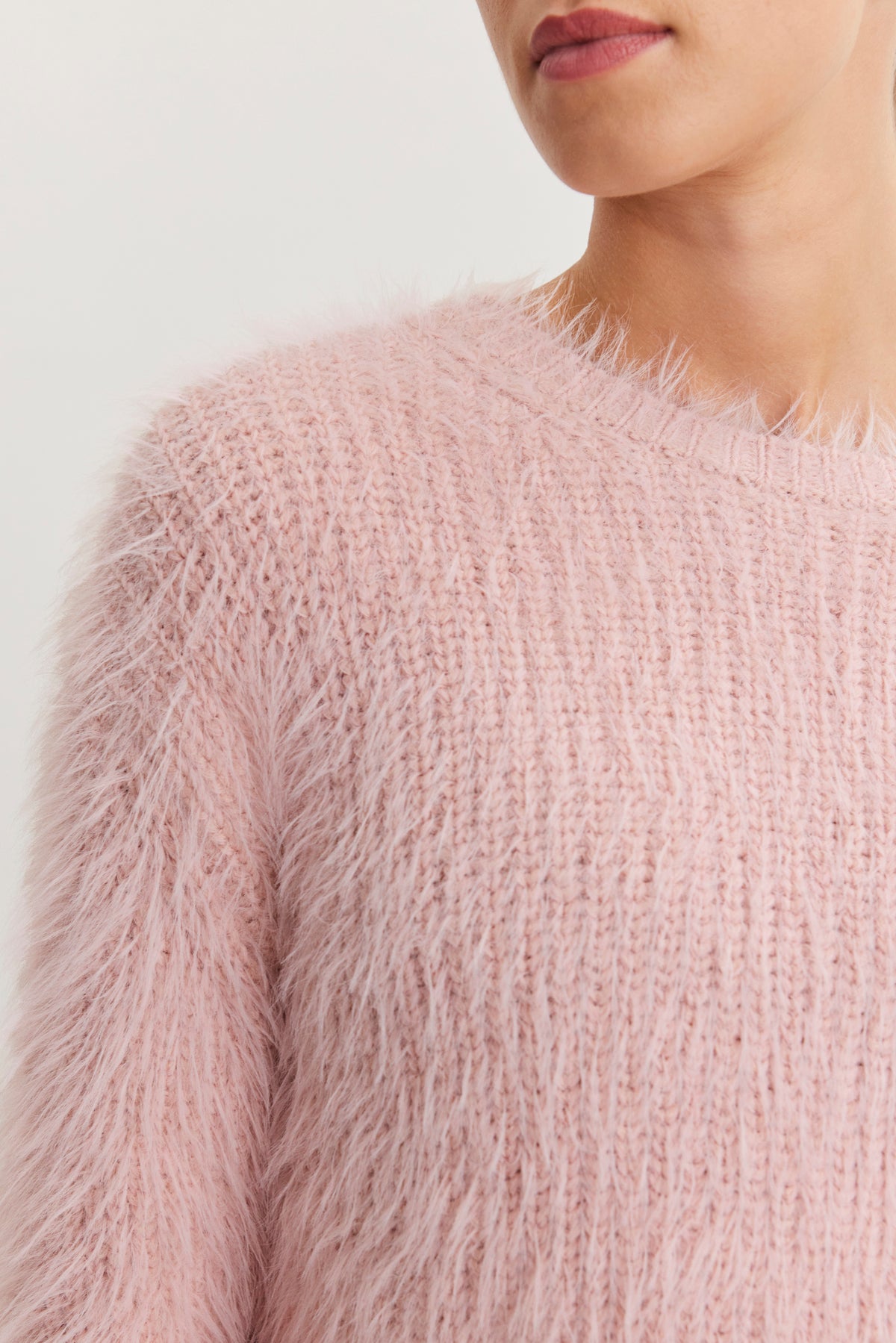 A person is wearing the MAYLIE FEATHER YARN SWEATER from Velvet by Graham & Spencer, showcasing its soft, fuzzy pink texture and crew neckline. The close-up highlights its irresistible feel.-38483622953153