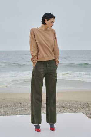 A woman is standing on a beach wearing a Velvet by Jenny Graham VENTURA PANT, a cotton twill wide leg pant.