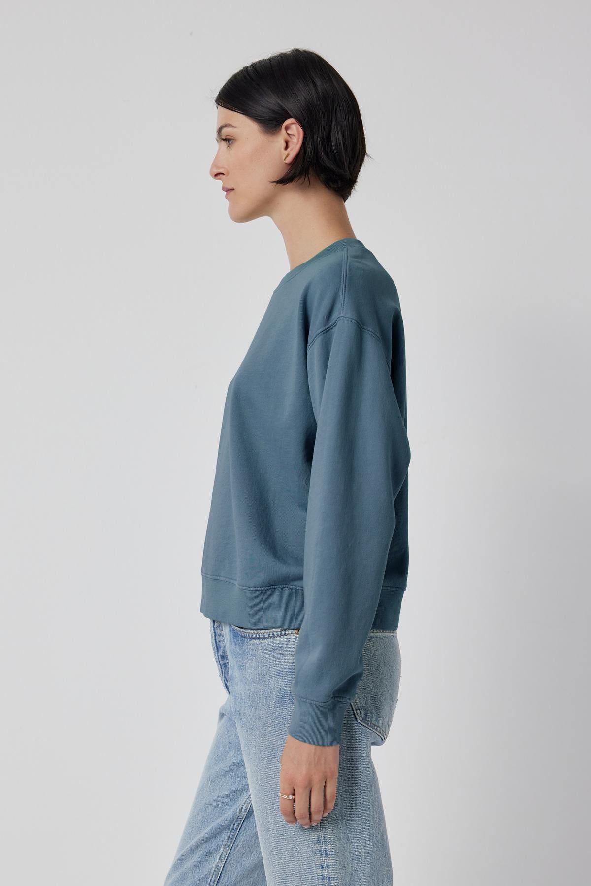   The model is wearing a dropped shoulder blue YNEZ SWEATSHIRT made of organic fleece by Velvet by Jenny Graham. 