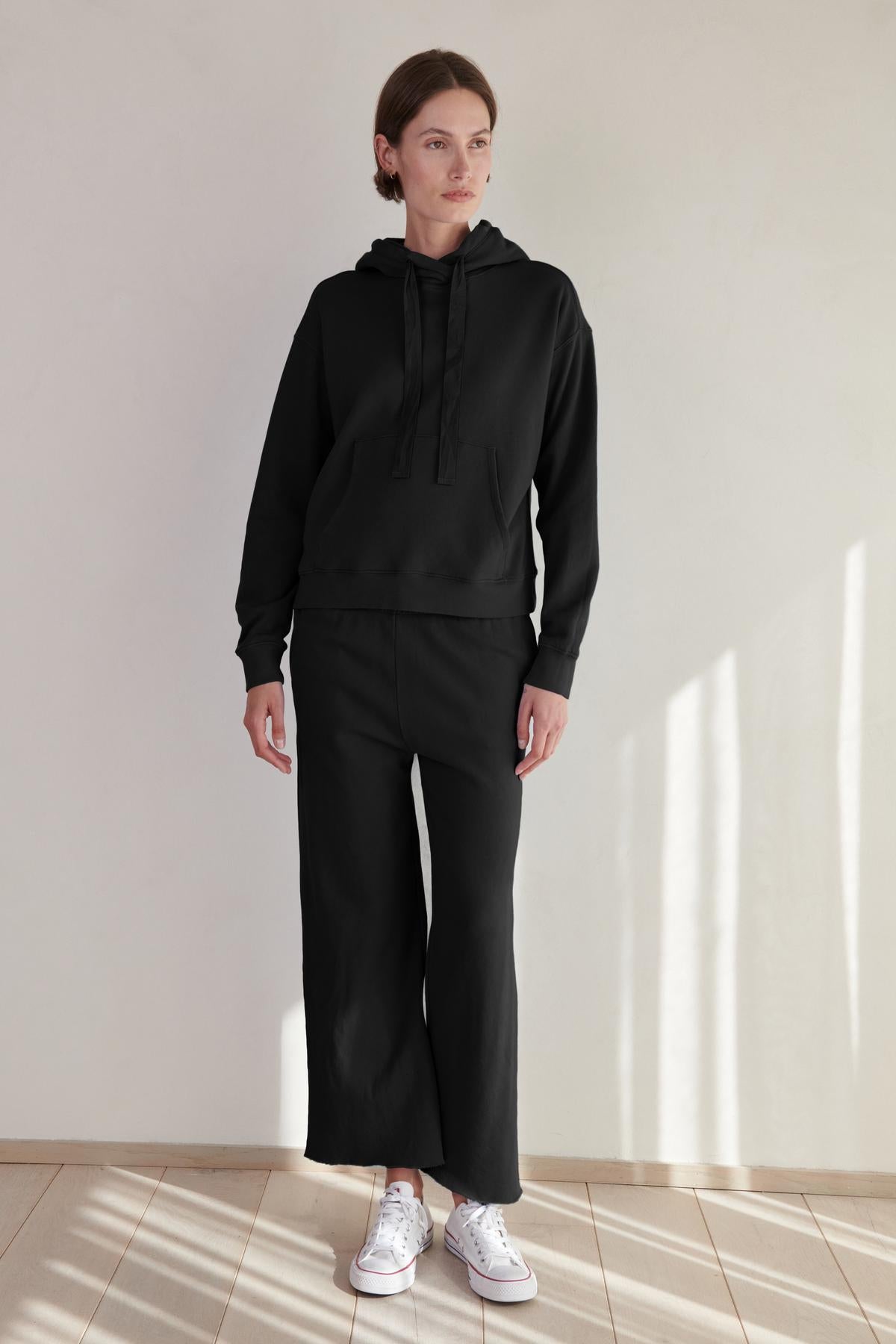   A woman wearing an OJAI HOODIE by Velvet by Jenny Graham and sweatpants. 