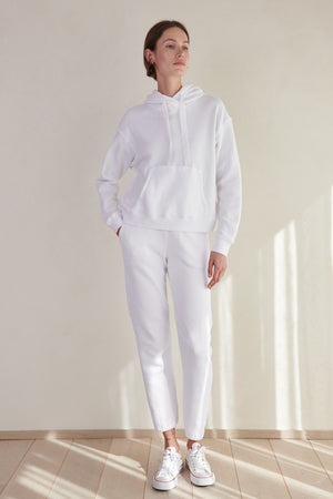 a woman wearing ZUMA SWEATPANTS by Velvet by Jenny Graham and a white hoodie.