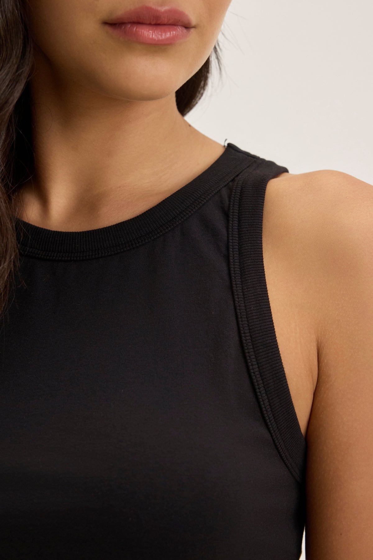   A person is shown from the shoulders up, wearing the GREER TANK TOP by Velvet by Graham & Spencer, crafted in organic cotton jersey against a plain background. 