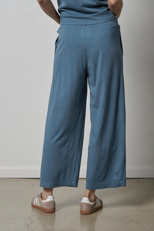 The back view of a woman wearing Velvet by Jenny Graham's PISMO PANT, a pair of blue wide leg pants with elastic waist and slash pockets.