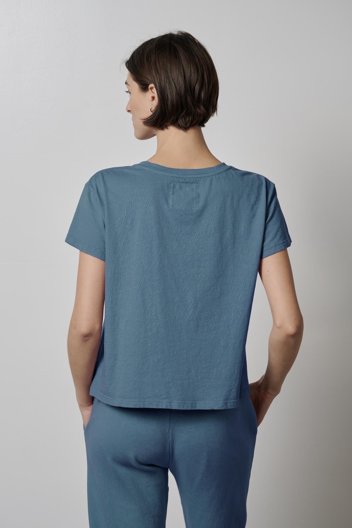   The back view of a woman wearing a blue Velvet by Jenny Graham TOPANGA TEE and pants. 