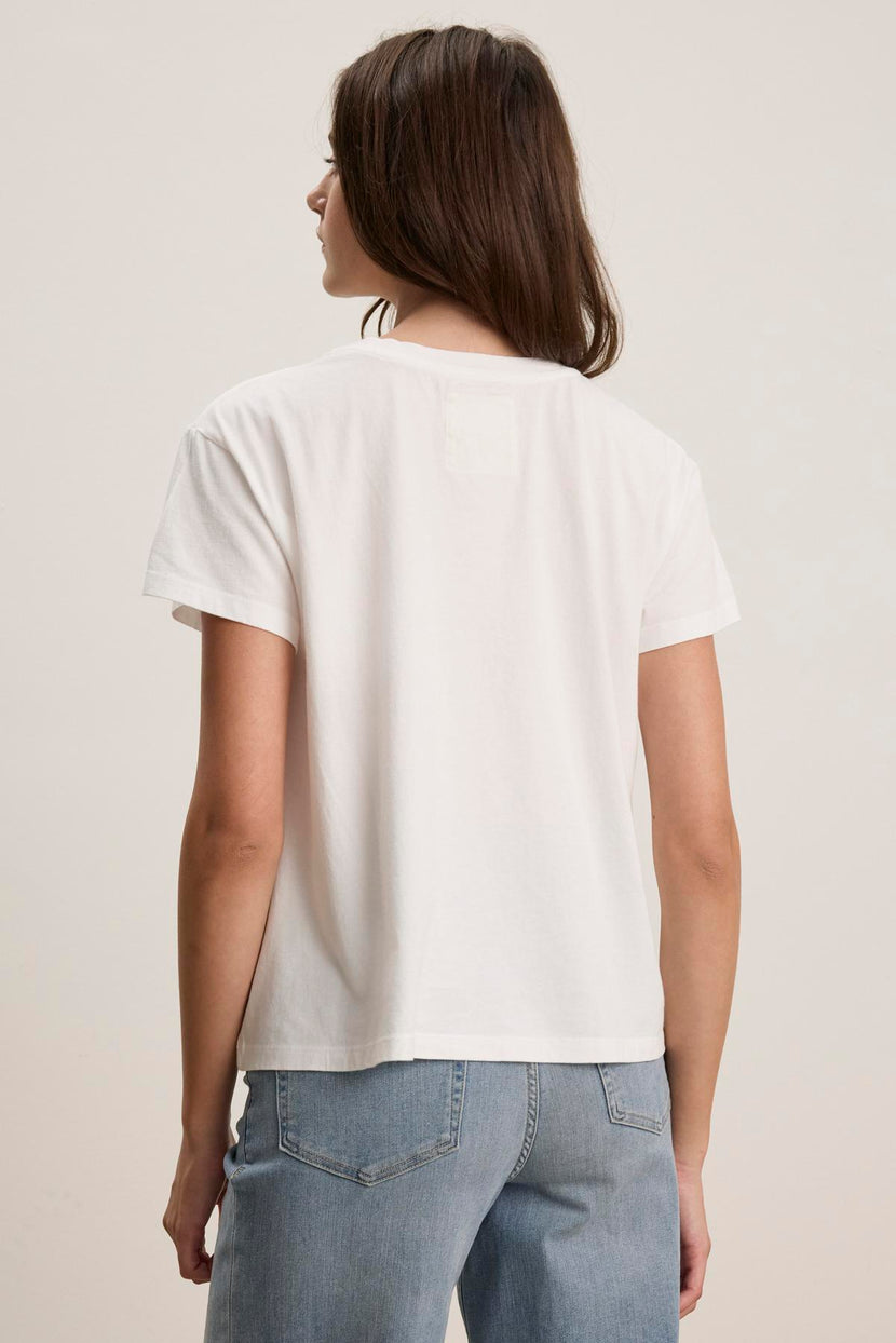 The individual is wearing the TOPANGA TEE by Velvet by Jenny Graham, which is a relaxed-fit white T-shirt made from organic cotton, paired with blue jeans and facing away.