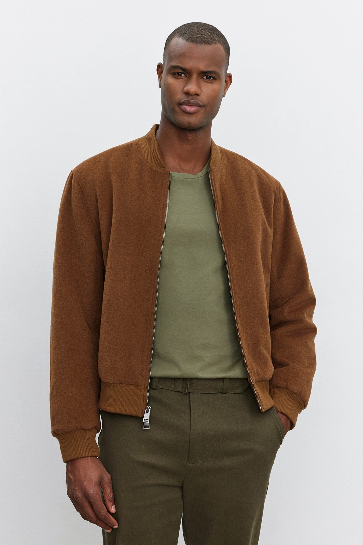 A man wearing a Velvet by Graham & Spencer FRAZIER BOMBER JACKET in a brown wool blend over a green shirt stands in front of a plain background.-37893889917121