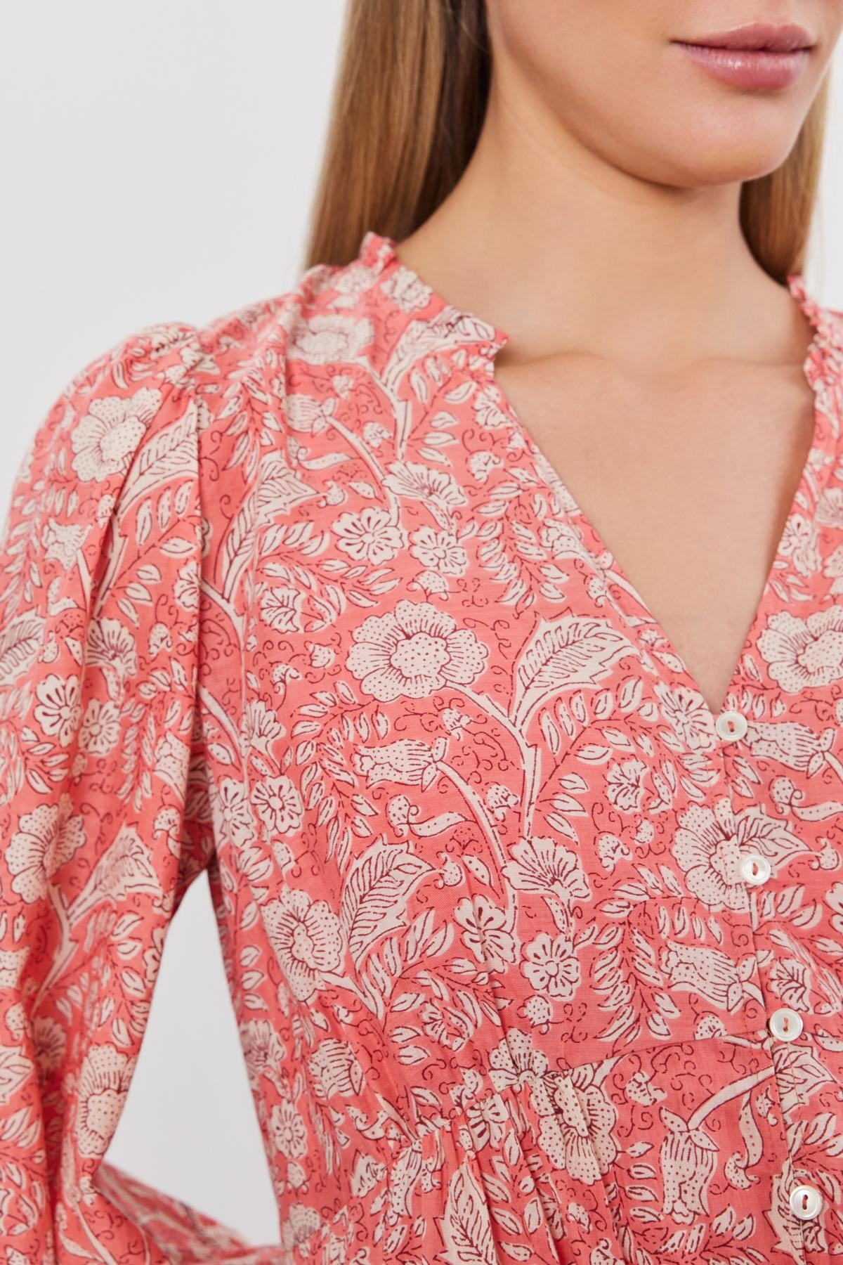   Close-up of a woman wearing a pink floral printed cotton voile MARY DRESS with a v-neckline and button details by Velvet by Graham & Spencer. 