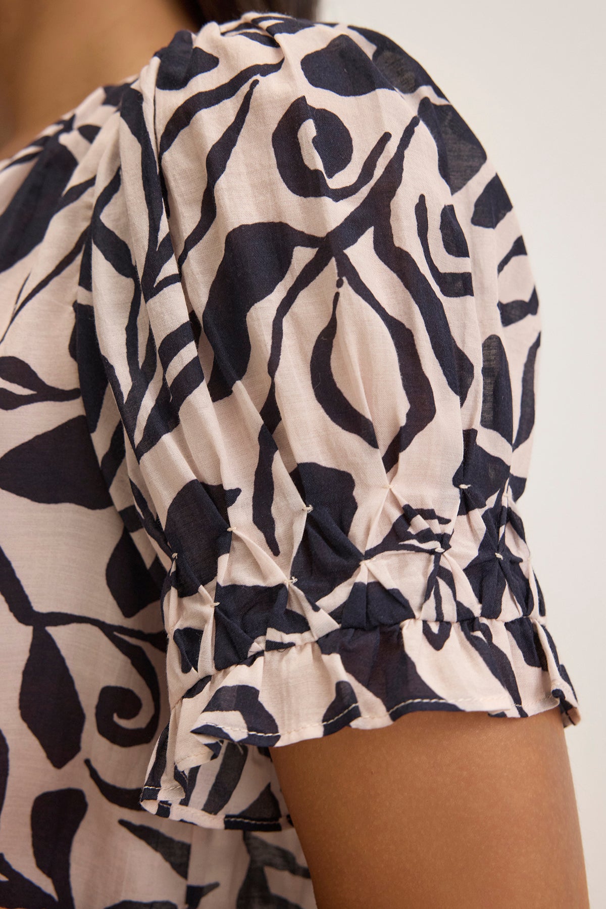   A close-up of the puffed sleeve with ruched detailing on the LESLIE TOP by Velvet by Graham & Spencer, featuring a black and white abstract pattern. 