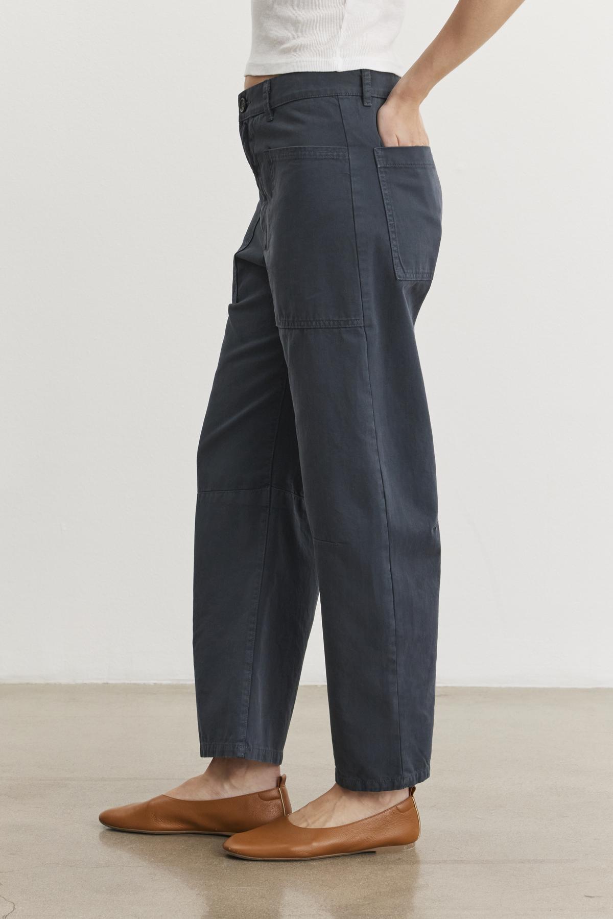 A person wearing Velvet by Graham & Spencer's Brylie Sanded Twill Utility Pant and brown flats stands casually against a plain background, exuding effortless style.-38512693018817