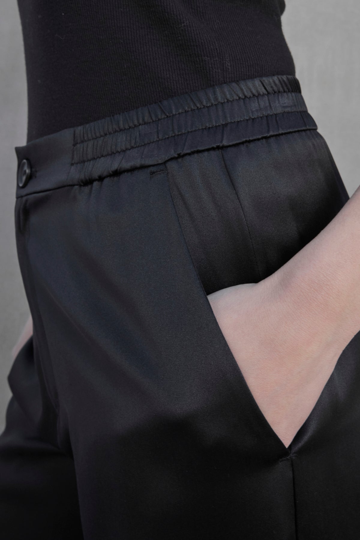   Close-up of a person wearing the Velvet by Jenny Graham Modesto Silk Charmeuse Pant, which features an elastic waistband and a hand placed in the pocket. 