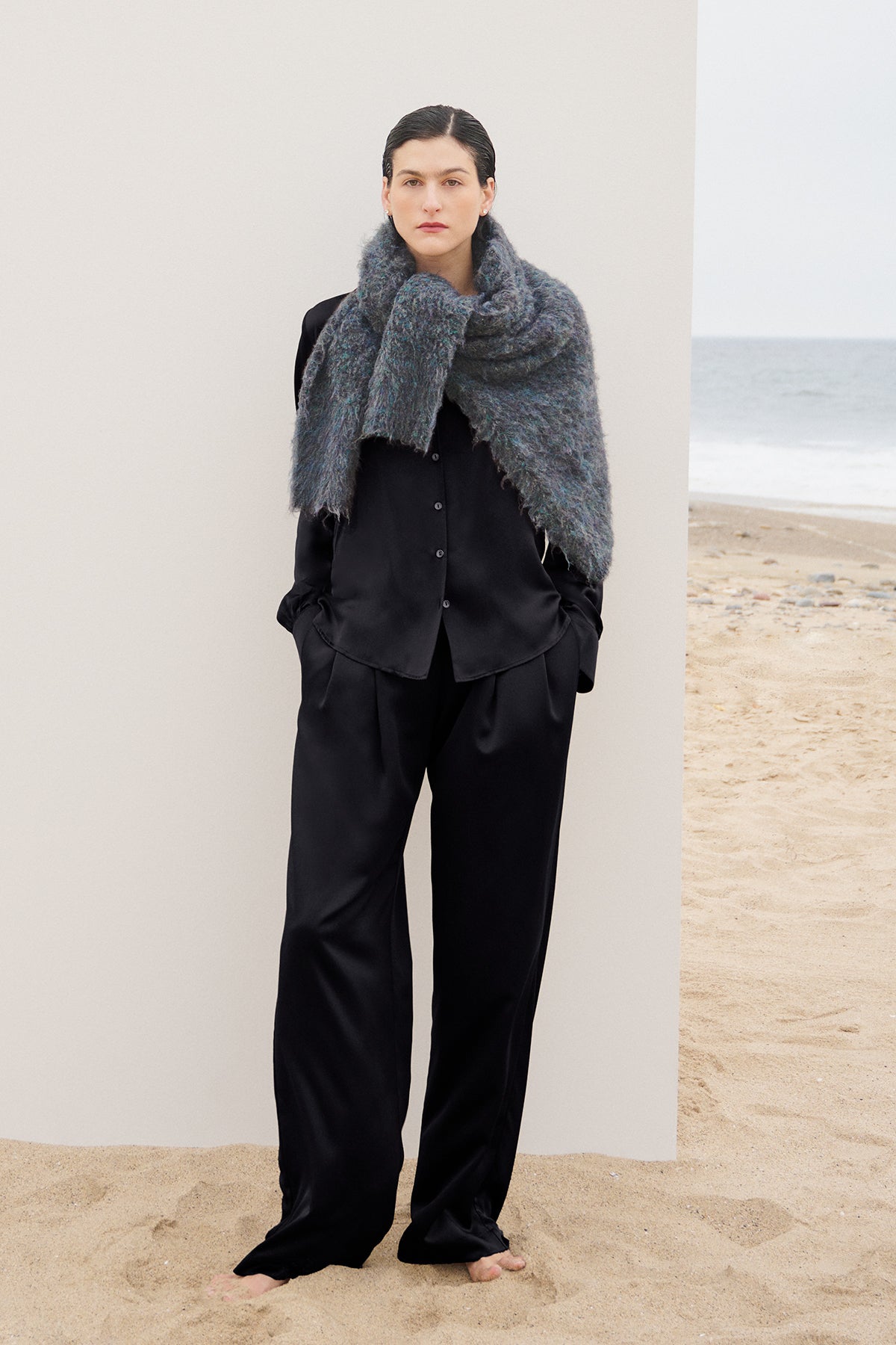   A woman wearing Velvet by Jenny Graham's timeless black pants and a scarf on the beach. 