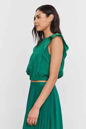 Profile view of a woman in a green ruffled Amora Top by Velvet by Graham & Spencer, with a crew neckline, looking to the side against a white background.