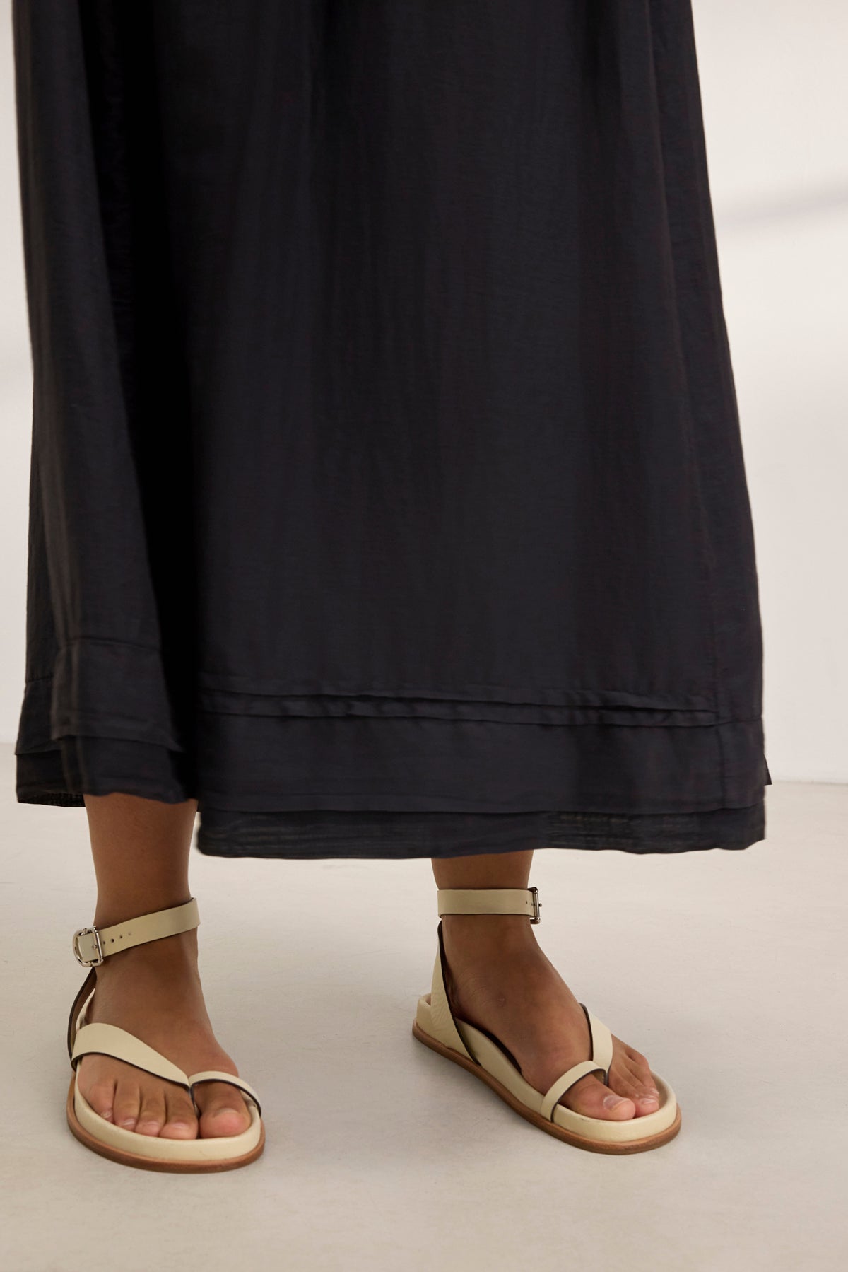   Dressed in a BAYOU SILK COTTON VOILE DRESS by Velvet by Graham & Spencer, paired with beige ankle strap sandals, this ensemble epitomizes versatile style as it rests effortlessly on a light surface. 