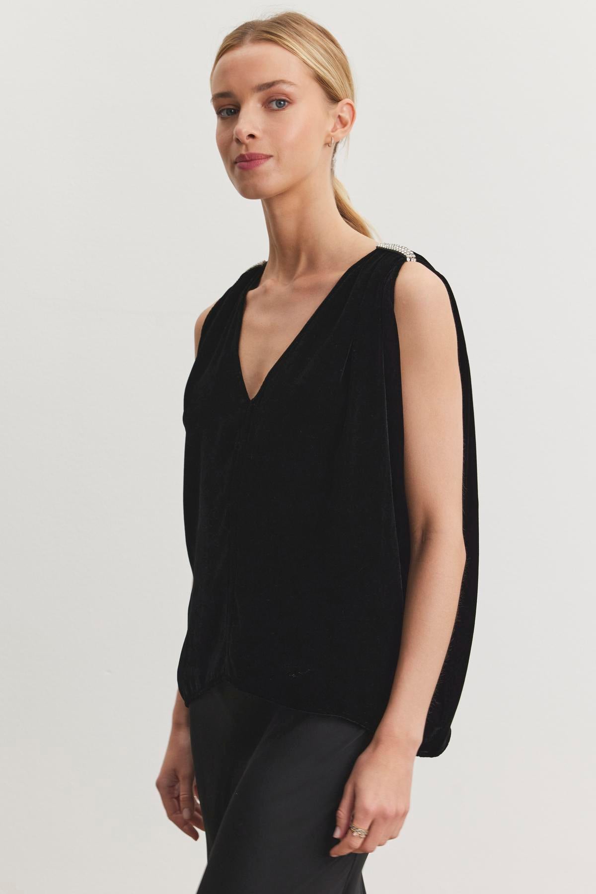   Dressed elegantly for holiday gatherings, a person in the ADELLE SILK VELVET TOP from Velvet by Graham & Spencer stands against a plain background. 