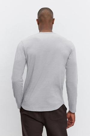 An individual wearing the KAI TEE in gray, designed by Velvet by Graham & Spencer, paired with dark pants is photographed from behind against a plain background, highlighting its timeless design.