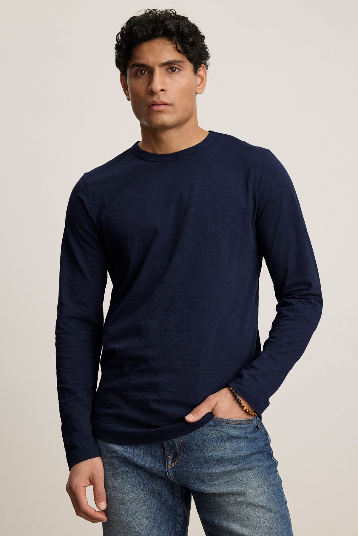 A model wearing Velvet by Graham & Spencer's KAI TEE, featuring a crew neckline and long sleeves, paired with jeans against a plain background.-38807449272513