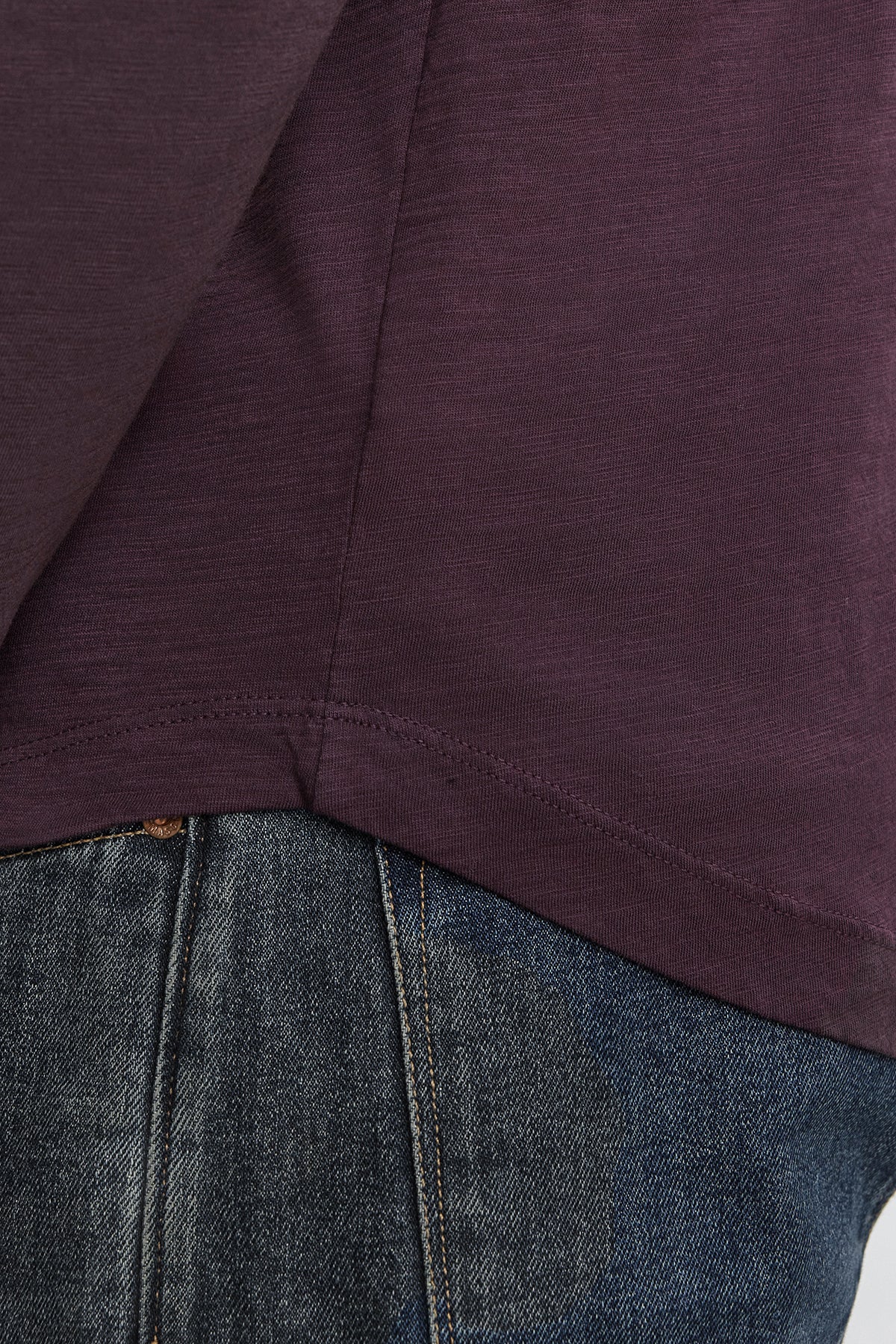 Close-up photo showing the lower part of a person wearing a dark purple KAI TEE by Velvet by Graham & Spencer and dark blue denim jeans.-37893903417537