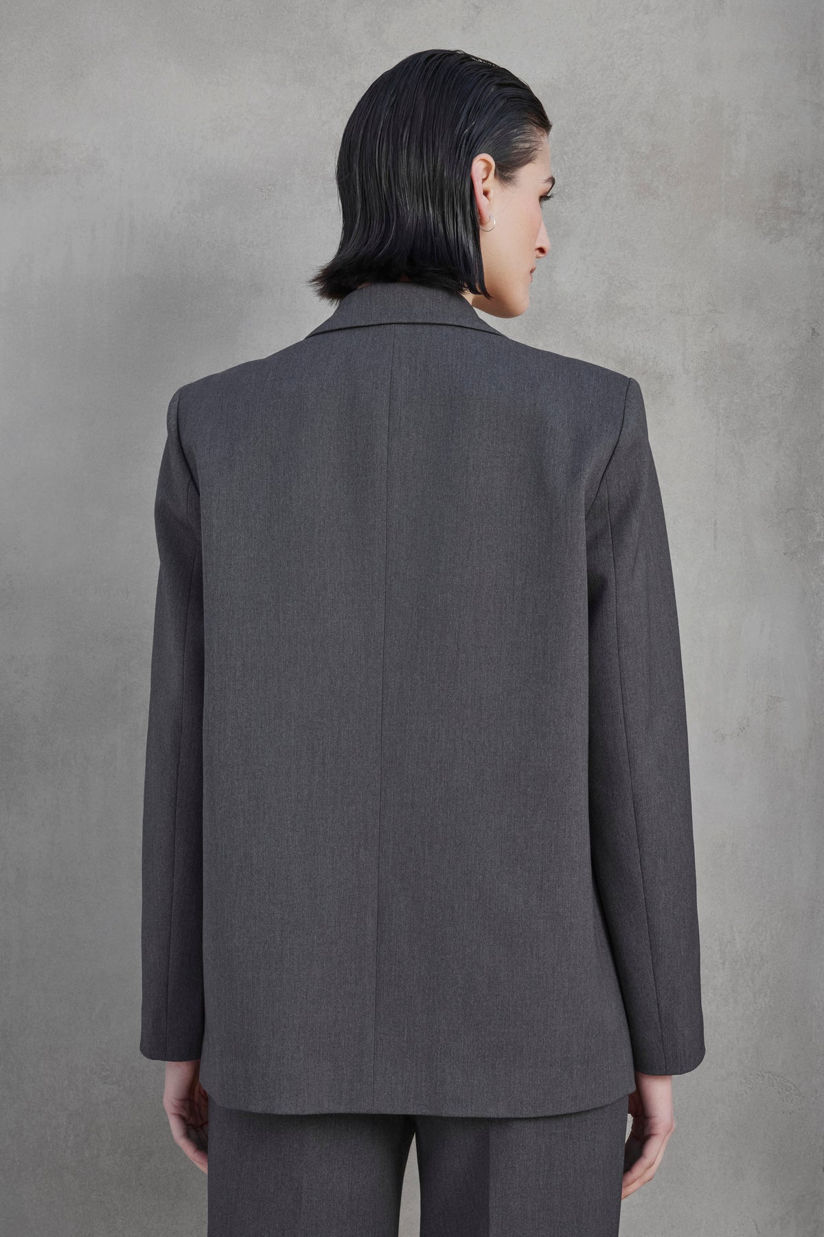   A person with short black hair is shown from behind wearing the Velvet by Jenny Graham REXFORD BLAZER and matching pants against a plain gray background. 