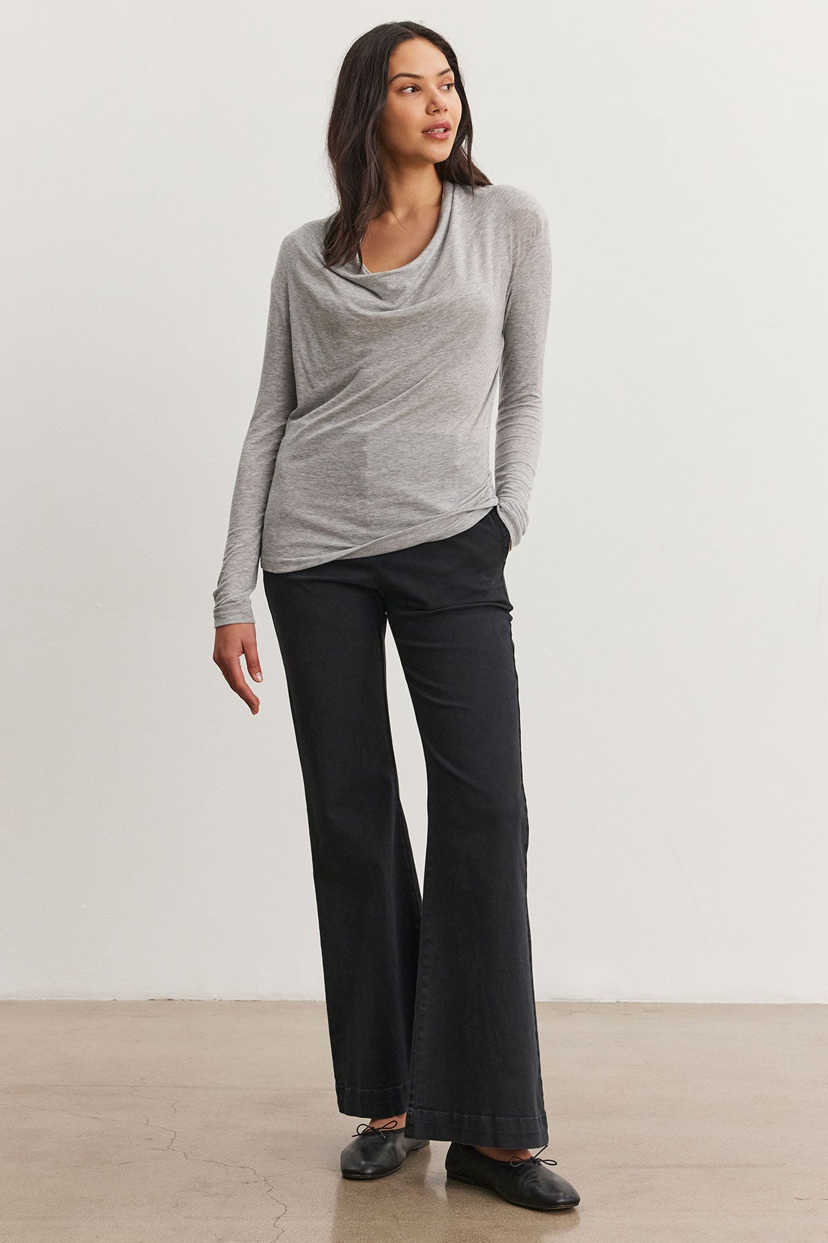   A woman in a PATTY TEE by Velvet by Graham & Spencer, a gray Tencel™ knit top, and black wide-leg pants stands against a plain white background. 